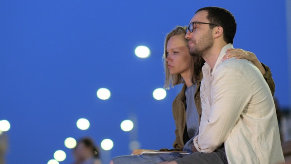 Worried students sitting on a bench in a park.