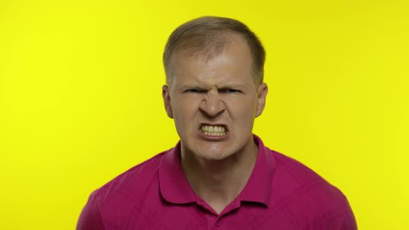 Portrait of Young Caucasian Man Posing in Pink T-shirt. Handsome Guy Screams and Gets Angry