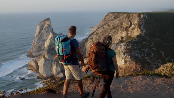 Excited Couple with Camping Backpacks Walking on Mountain Path