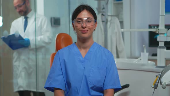 Nurse Smiling at Camera Sitting in Dental Office