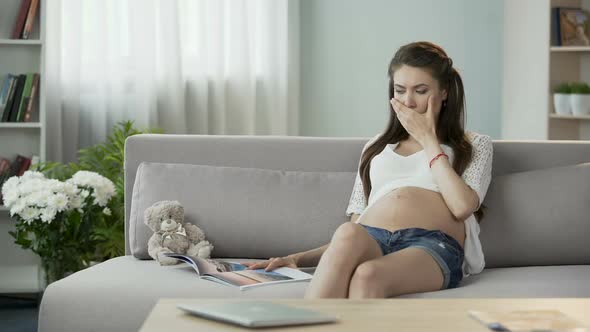 Mother-To-Be Sitting on Couch and Reading Magazine, Having Disturbing Hiccups