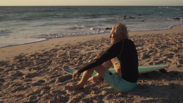 Senior man sitting on the sand at the beach