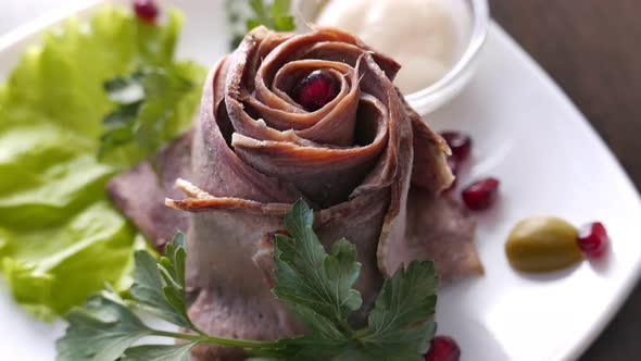 Cold Sliced Meat on a White Plate with Pomegranate Seeds and Sauce