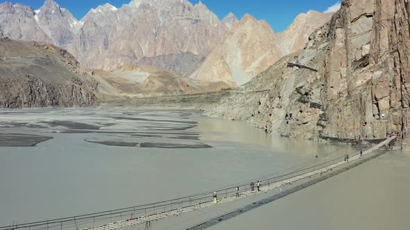 Aerial drone of tourists crossing the famous Hussaini bridge in Hunza Pakistan with a fast river flo