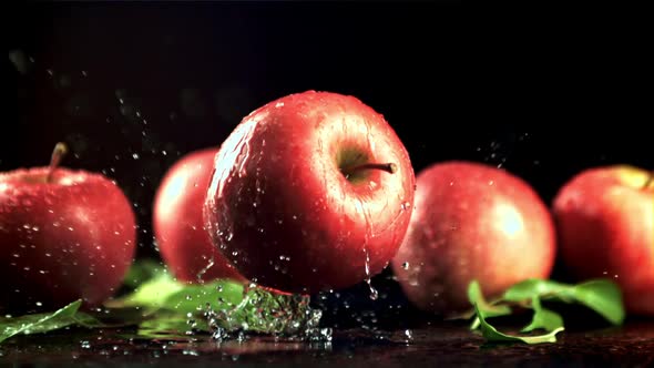 A Fresh Red Apple Falls on a Table with Splashes of Water