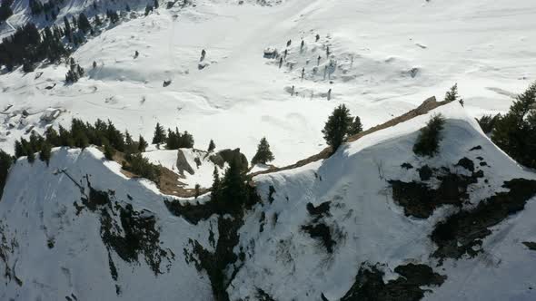 High angle jib down of trees on top of mountain overlooking snow covered valley