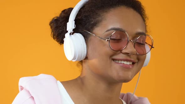 Pretty Young Woman in White Headphones Enjoying Music Sound on Yellow Background