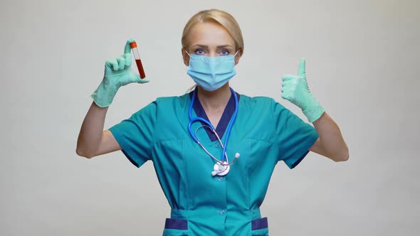 Medical Doctor Nurse Woman Wearing Protective Mask and Latex Gloves - Holding Blood Test Tube