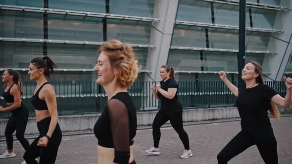 Portrait of Energetic Curly Blonde Woman Dancing in Group Class with Her Girlfriends Outdoor on a