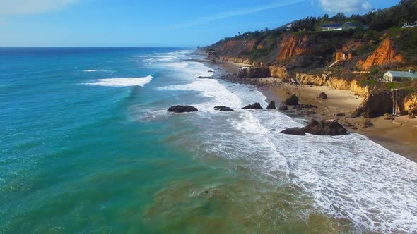 Drone camera moving over sandy shore at sunny day near El Matador Beach, Malibu, Califronia, USA