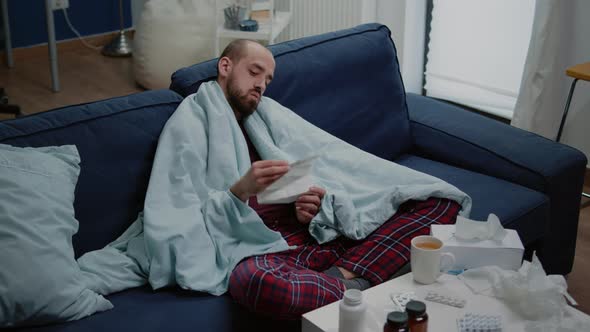 Man with Sickness Reading Medicament Information Leaflet