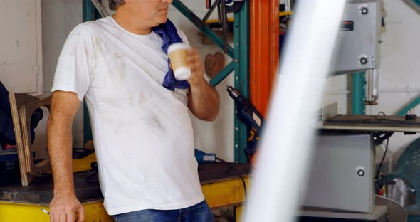 Male mechanic having coffee in garage 
