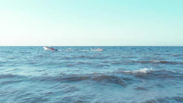 Two Boats Float in Different Directions in the Sea on the Waves