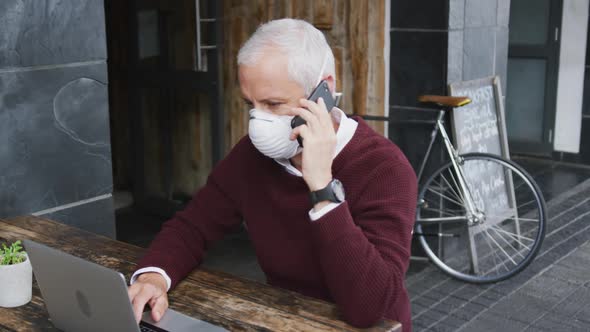 Caucasian man out and about in a coffee wearing a face mask against coronavirus