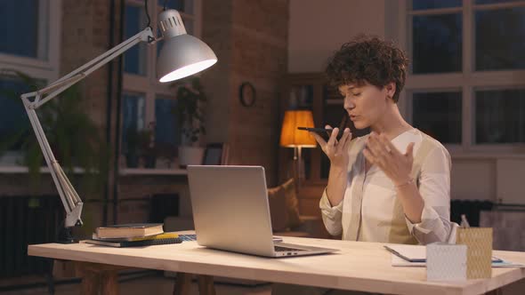 Woman Talking on Phone while Working from Home