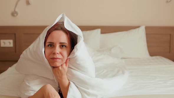Young Woman Wrapped in Blanket Lying on Bed and Watching Tv