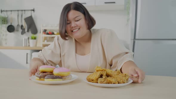 Asian young oversize big women feel happy for unhealthy foods on plate ready to eat in kitchen