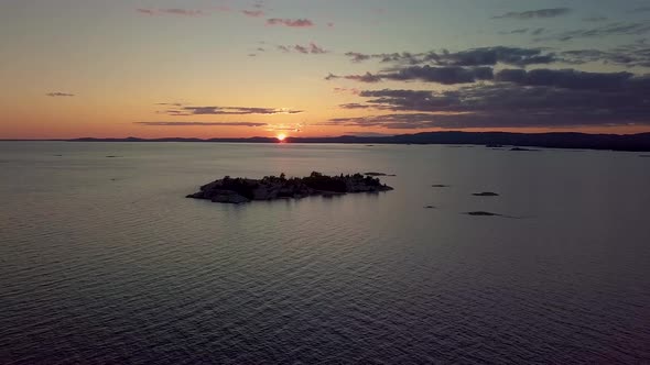 High View of Rocky Pine Tree Island in Blue Lake at Sunset, Drone Aerial Wide Dolly In. Colorful Clo