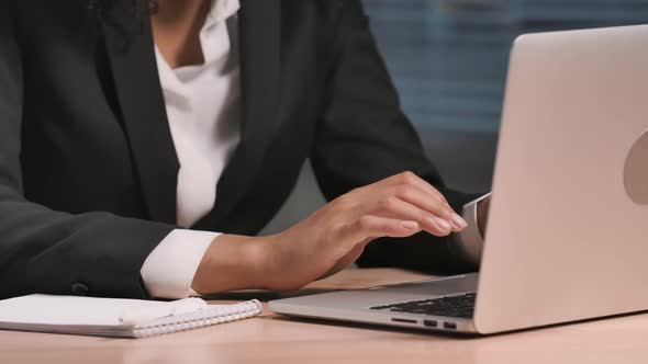 Portrait of African American Woman Looking at Laptop Screen and Making Notes in Notebook