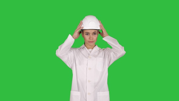 Woman engineer in white robe and white hard hat walking