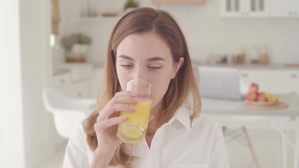 Close-up Face of a Young Beautiful Caucasian Woman Tasting Orange Juice and Smiling with