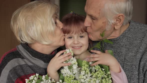 Grandfather and Grandmother Kissing on Head Their Kid Granddaughter at Home