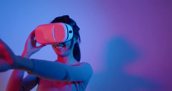 Woman Playing Game with Joystick and Enjoy with Virtual Reality with Pink and Blue Lighting