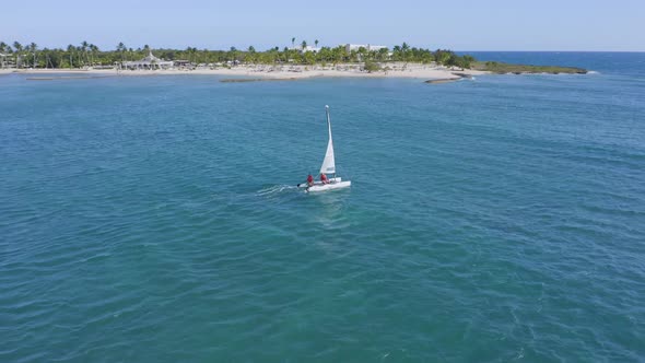 Boat sailing in azure Caribbean just off palm fringed beach; aerial