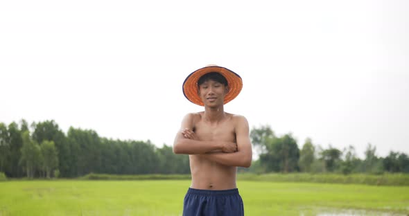 Young farmer topless standing and arms folded in rice field