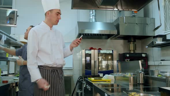 Chef Reading Something From His Phone and Talking To One of the Cook Trainees