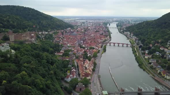 Aerial dolly out of Heidelberg village and Castle ruins next to Neckar River and its bridges between