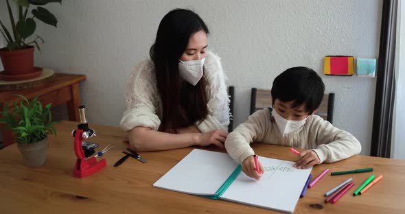 Asian female teacher clap with hands while little kid doing drawing activities