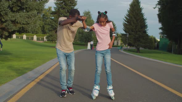 Father Teaching Daugther To Roller Skating in Park