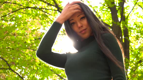 A Young Asian Woman Strikes Poses for The Camera in A Park