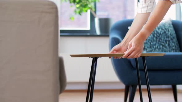 Woman Placing Coffee Table Next To Sofa at Home