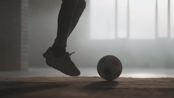 The Silhouette of a Football Player Training in an Underground Parking Lot in the Sun and Rising