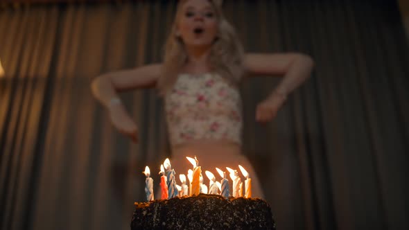 Beautiful Woman Blowing Out Candles on a Festive Cake.