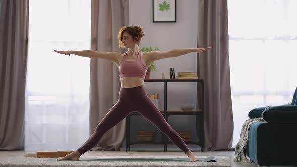 Sportswoman is Performing Yoga Asana at Home Training Alone in Living Room at Morning Keeping Fit