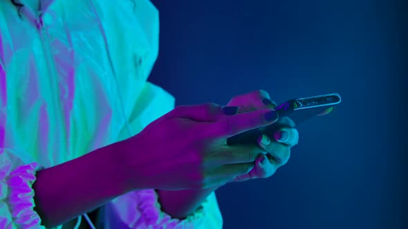 African American Woman Texting Her Smartphone Against Dark Studio