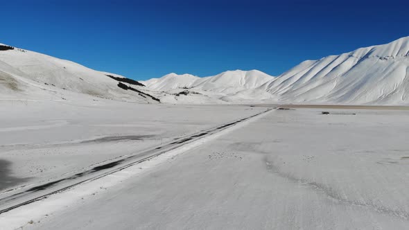 Panning shot over frozen landscape with Piano Grande, Castelluccio