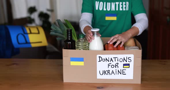 Volunteer preparing food box for ukrainian war refugees - Humanitarian help and aid concept