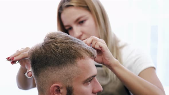 Hairdresser Doing Haircut for Customer Using Scissors in Salon