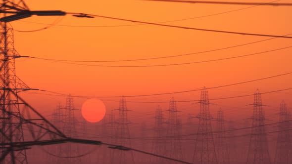 Loopable shot of high voltage electricity pylons during sunset. Bright red sky,