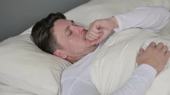 Sick Middle Aged Man with Cough Laying in Bed