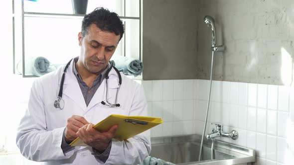 Mature Male Vet Filling Medical Papers Smiling To the Camera