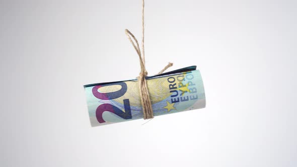 Rolled Euro bills tied with jute rope and swinging 