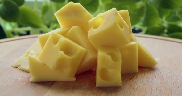 Closeup Video of a Several Pieces of Aromatic Milk Cheese Rotate on a Wooden Stand Over Natural