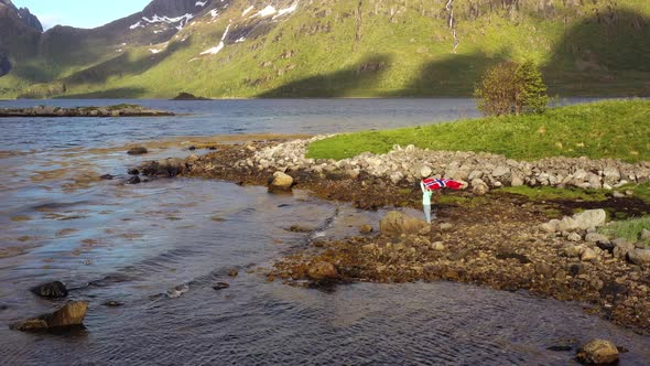 Woman with a Waving Flag of Norway on the Background of Nature