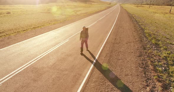 Flight Over Hitchhiker Tourist Walking on Asphalt Road