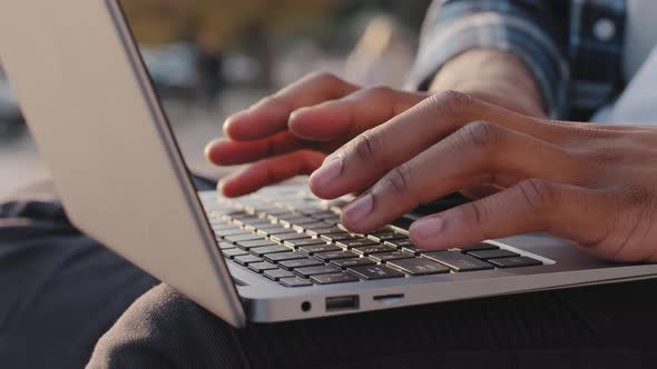 Close Up Male African American Worker User Hands Fingers Quickly Typing on Laptop Sit Outdoors City